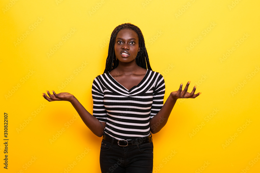 Satisfied smiling african american woman raises hands yellow background Satisfied smiling african american woman raises hands yellow background
