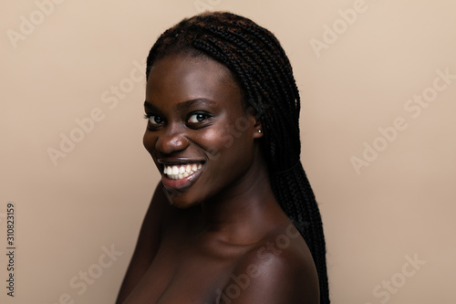 Portrait of a young beautiful african woman perfect skin isolated on beige. Skin care.