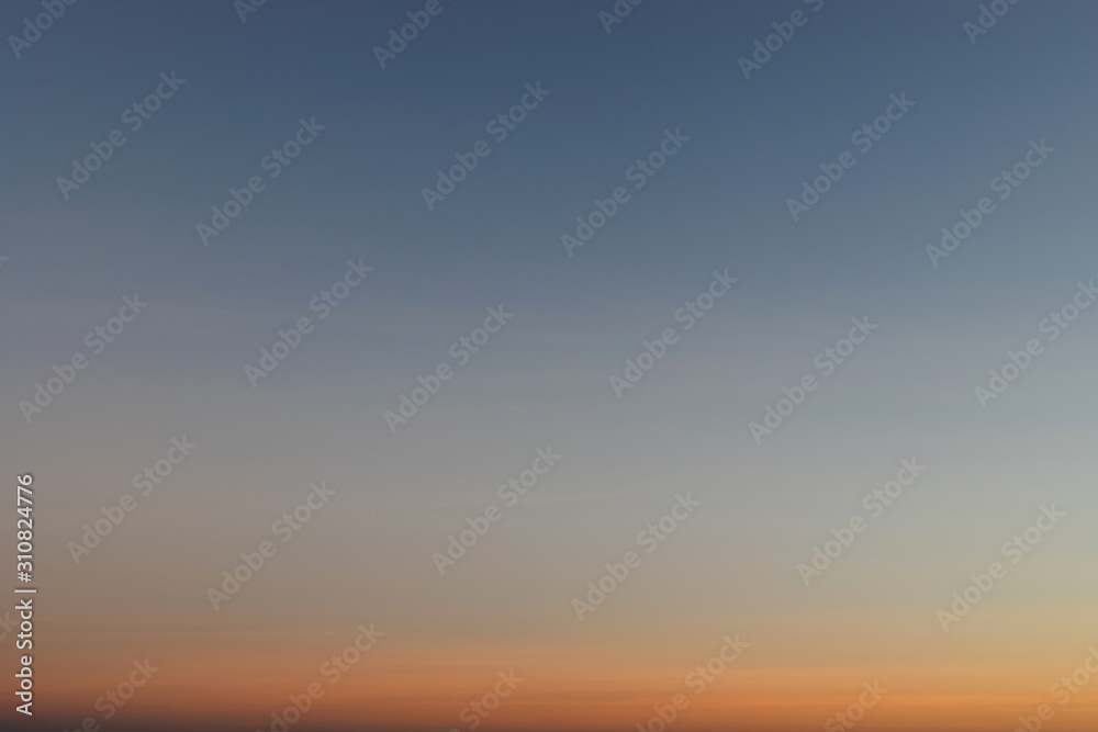 Heaven at early morning with copy space. Smooth orange blue gradient of dawn sky.Sunset, sunrise backdrop.Predawn clear sky with orange horizon and blue atmosphere.  Background of beginning of day.