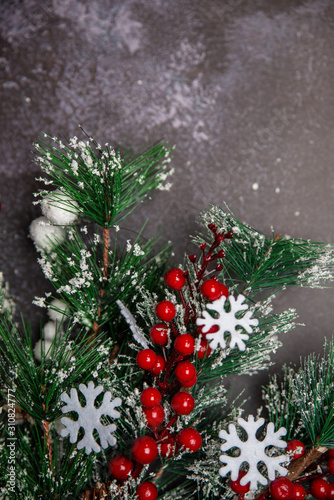 Christmas fir twigs with red berries and snowflakes on dark background
