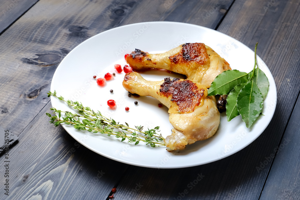 On a white dish on a dark wooden tabletop are two fried chicken