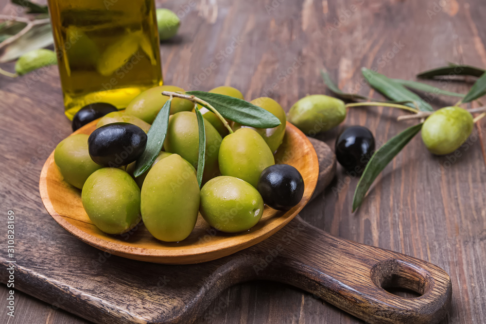 Green and black olives in small wooden plate Green and black olives in small wooden plate