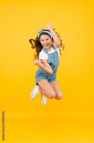 Active girl feel freedom. Fun and relax. feeling free. carefree kid on summer holiday. time for fun. retro beauty in mid air. Jump of happiness. small girl jump yellow background. full of energy. photo