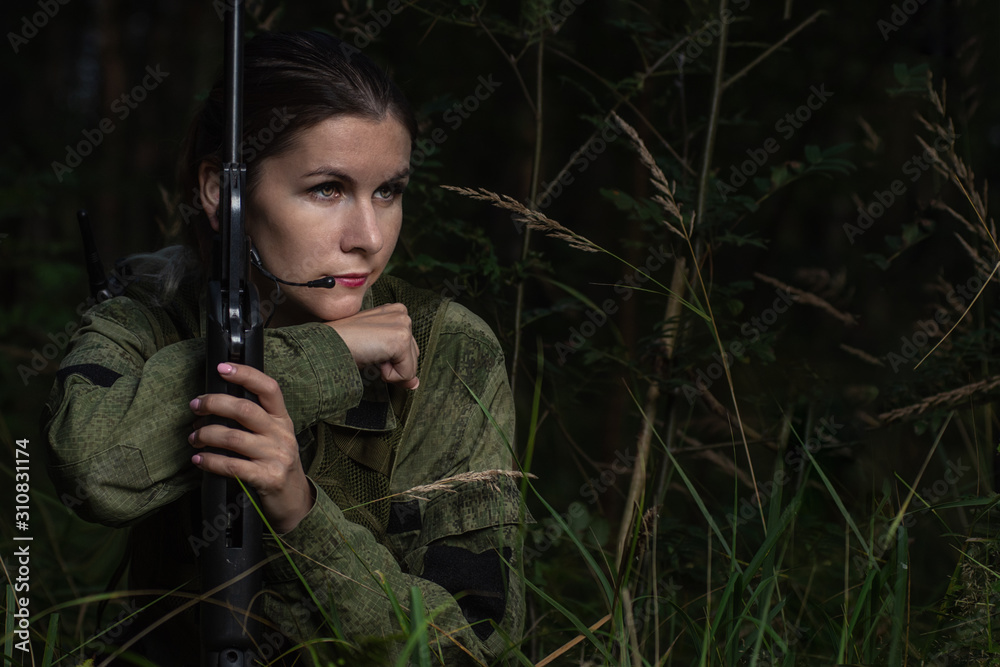 Portrait of beautiful army girl, soldier woman with rifle with optical sight and military uniform in the forest