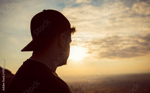 Silhouette of young man, standing alone, lonly by the sunset light