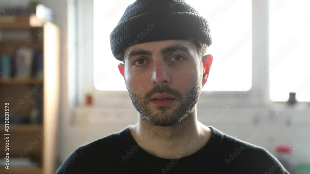 Close up portrait of young man in front of bright window inside room in slow motion Close up portrait of young man in front of bright window inside room in slow motion