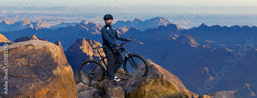 Conquering mountain peaks by cyclist in shorts and jersey on a modern carbon hardtail bike with an air suspension fork . Beautiful view from the mountain. Panoramic view for banner. 