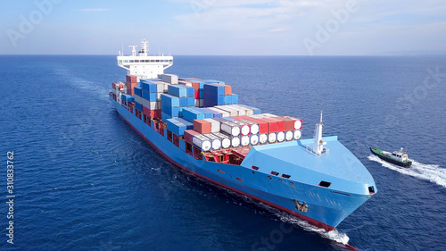 Large container ship at sea, loaded with various container brands. ULCV container ship sails on open water fully loaded with containers and cargo.