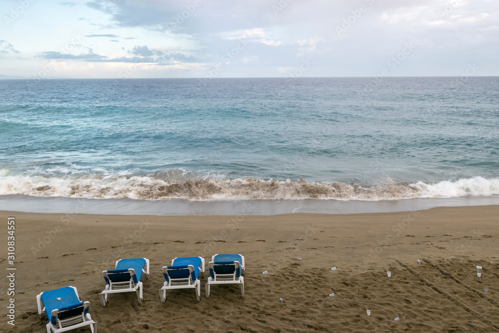 Four empty sun loungers stand on the ocean. plastic trash is scattered around. environmental protection concept Four empty sun loungers stand on the ocean. plastic trash is scattered around. environmental protection concept