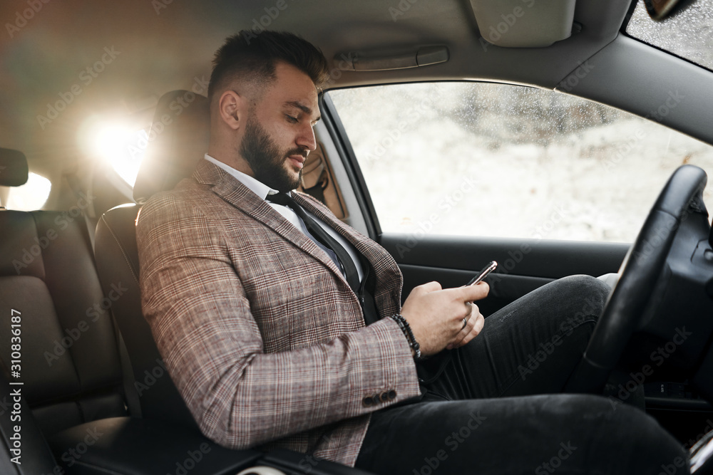guy businessman in car with laptop and phone