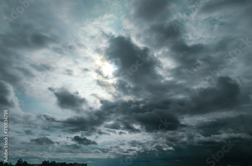 blue sky and dark black clouds, sun hiding behind the clouds in dramatic sky atmospheric moods background