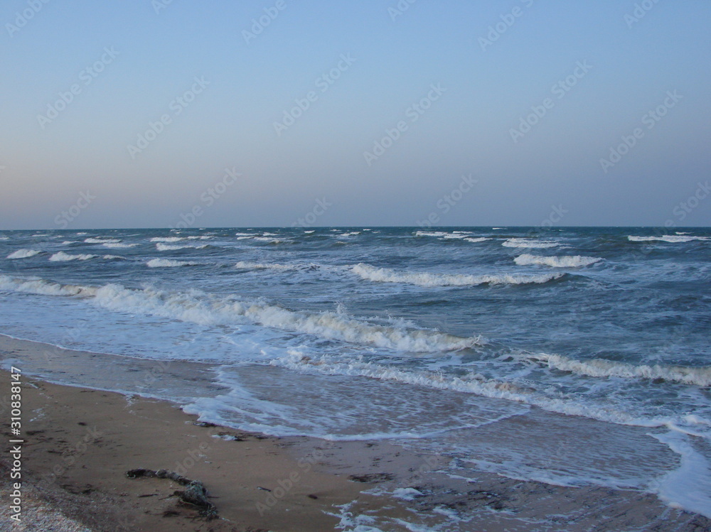 Landscape of snow-white foam of coastal sea waves gently stroking the sandy shore, under the rainbow colors of the sunset. Landscape of snow-white foam of coastal sea waves gently stroking the sandy shore, under the rainbow colors of the sunset.