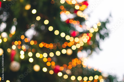 Blurry background of colorful Christmas tree with glowing lights on a white background.