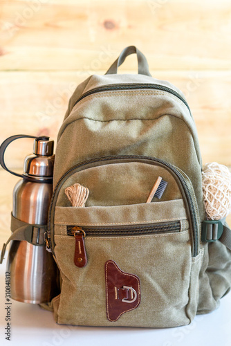 Zero waste travel. Backpack with stainless steel plastic free reusable water bottle, natural reusable cotton mesh grocery bag, eco-friendly bamboo toothbrush, rope natural jute string twine cord.