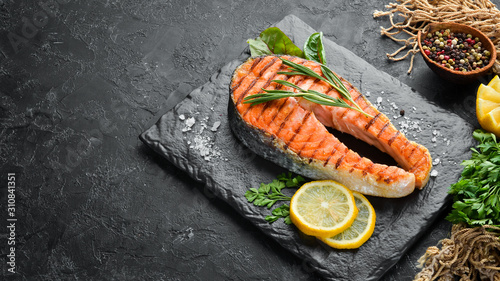 Grilled salmon steak on a stone plate. On an old background. Top view. Free copy space. photo