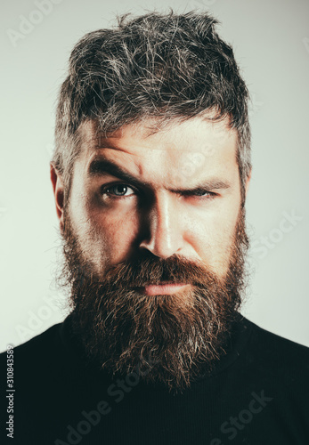 Serious stylish bearded man. Handsome young man isolated. Close up portrait of severe hot bearded guy with stylish hairdo. Isolated on grey background. Lifestyle people concept. Bearded man.