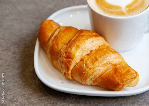 Latte art hot coffee with fresh baked butter croissant