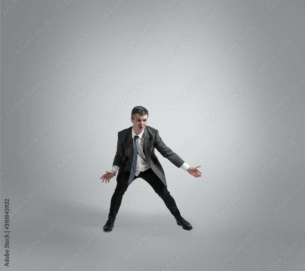 Dreams about big possibilities. Man in office clothes traines in football or soccer like goalkeeper on grey background. Unusual look for businessman in motion, action. Sport, healthy lifestyle.