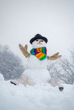 Snowman in a scarf and hat. Happy funny snowman in the snow. Winter background with snowflakes and snowman. Happy snowman standing in winter Christmas landscape