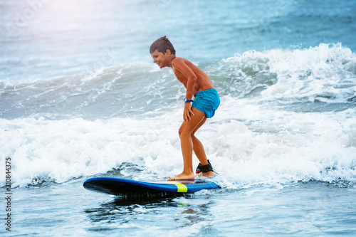 Fényképezés Little boy stand on the surfboard learn to ride