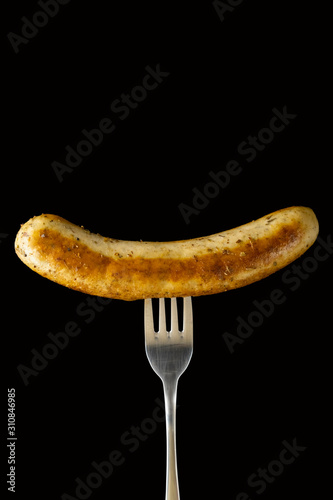 Delicious bratwurst sausage grilled with Italian mix herb on fork isolated on black background, Clipping path
