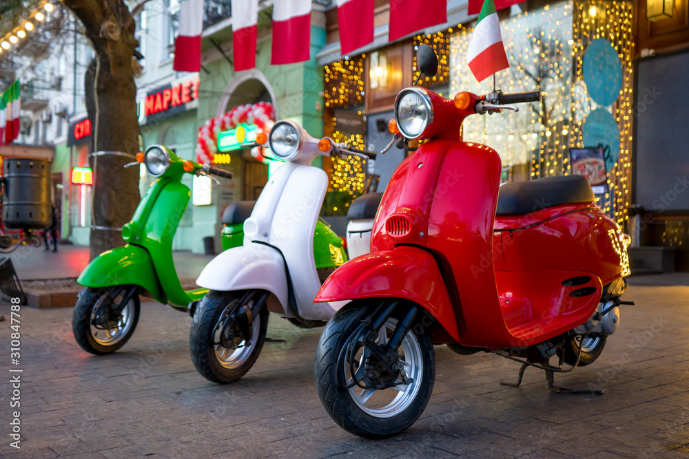  Retro vintage scooters stand near an Italian restaurant. Modern personal transport.