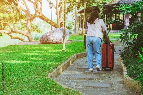 Female traveler tried to drag luggage through the rough paths in the garden. photo