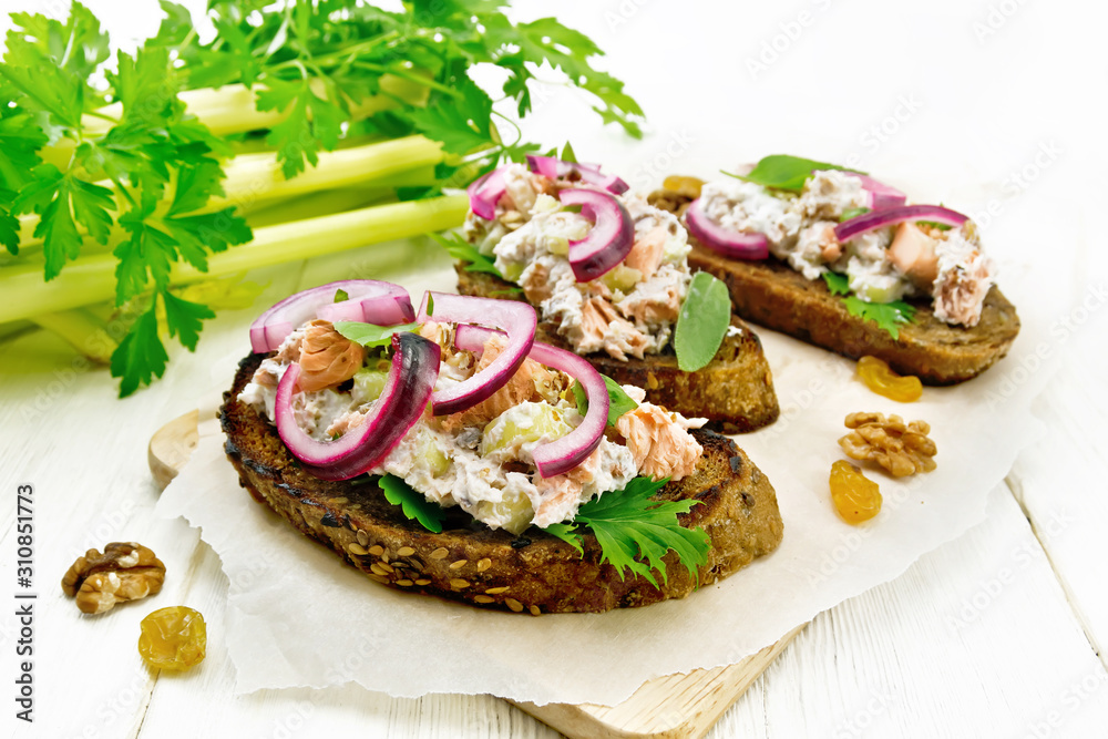 Bruschetta with fish and curd on light wooden board