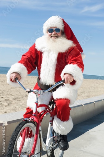 Santa Claus Riding Cycle By The Beach © moodboard