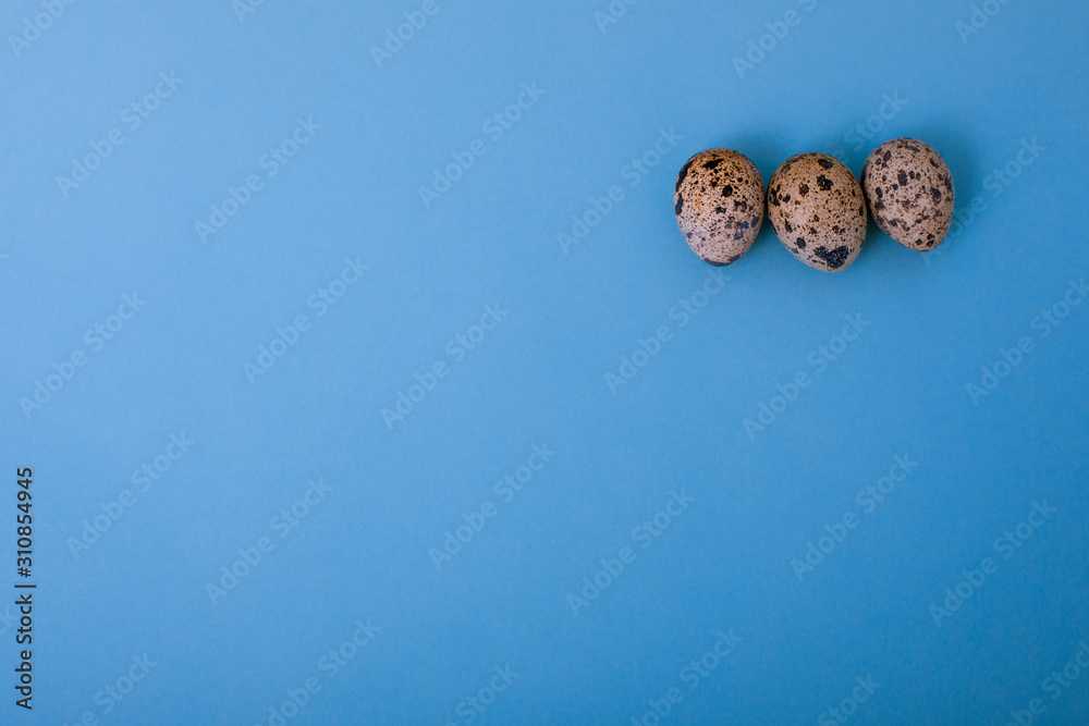 Quail eggs are on blue background. Easter card greeting. Flat lay. Copy space.