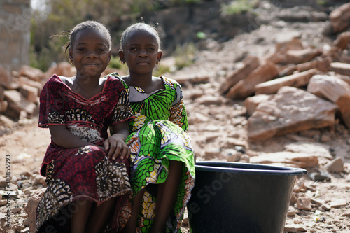 Two Gorgeous African Black Women Sitting Outdoors with Water Bucket