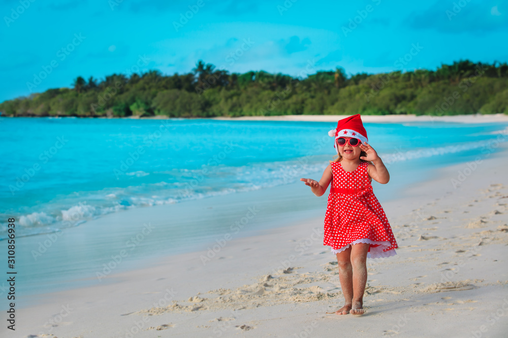 cute little girl sing and clap hands, celebrating christmas on tropical beach cute little girl sing and clap hands, celebrating christmas on tropical beach