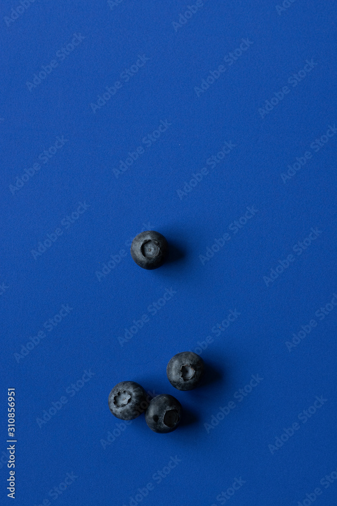 Blueberries on blue paper background, dark blue tones image with space for text, minimalist photo Blueberries on blue paper background, dark blue tones image with space for text, minimalist photo