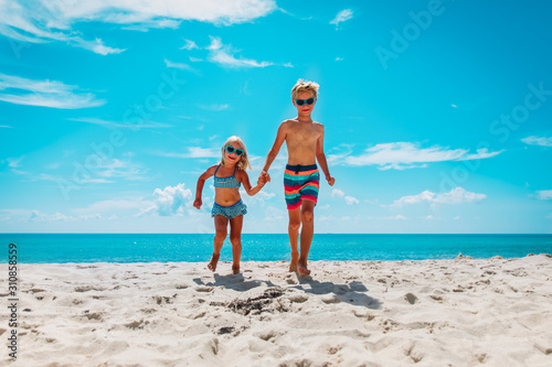 happy cute boy and girl running at beach, kids play at sea