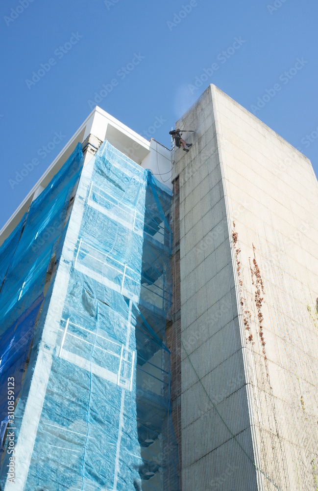 Fototapeta premium Rope access technician washing building facade