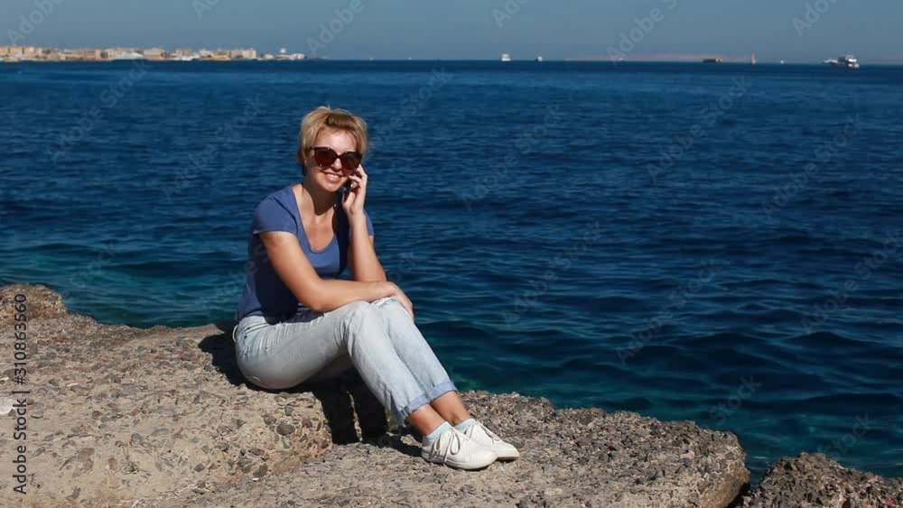 Young pretty traveler woman calling and talking phone, wifi connection on sunny beach Beautiful young woman has fun, uses a smartphone Young pretty traveler woman calling and talking phone, wifi connection on sunny beach Beautiful young woman has fun, uses a smartphone