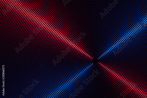 A close up macro photo of circular brushed steel metal texture with crossed red and blue lines