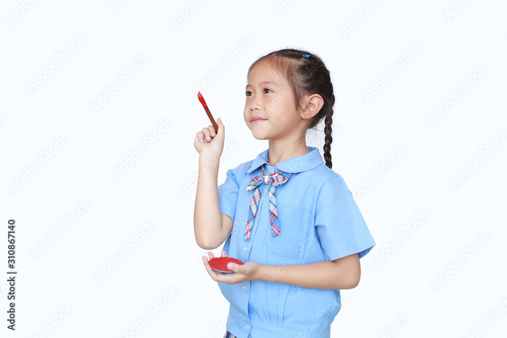 Asian little child girl in school uniform holding Red dipped paintbrush thinking of drawing something over white background. Asian little child girl in school uniform holding Red dipped paintbrush thinking of drawing something over white background.