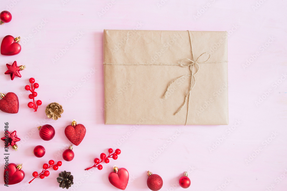 Pink wooden christmas background with gift box, fir-tree branch and red christmas decorations in the corner. Frame. View from above