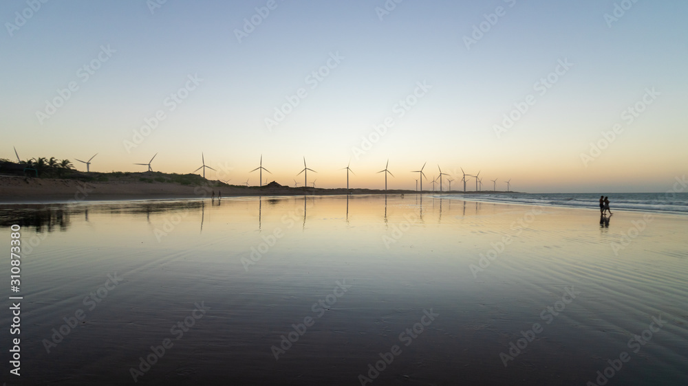 sunset on the beach with windmills in the background