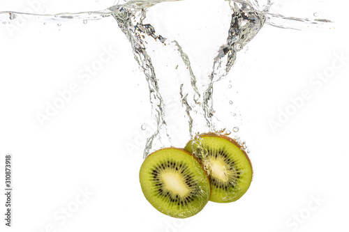 whole kiwi and sliced slices falling under water