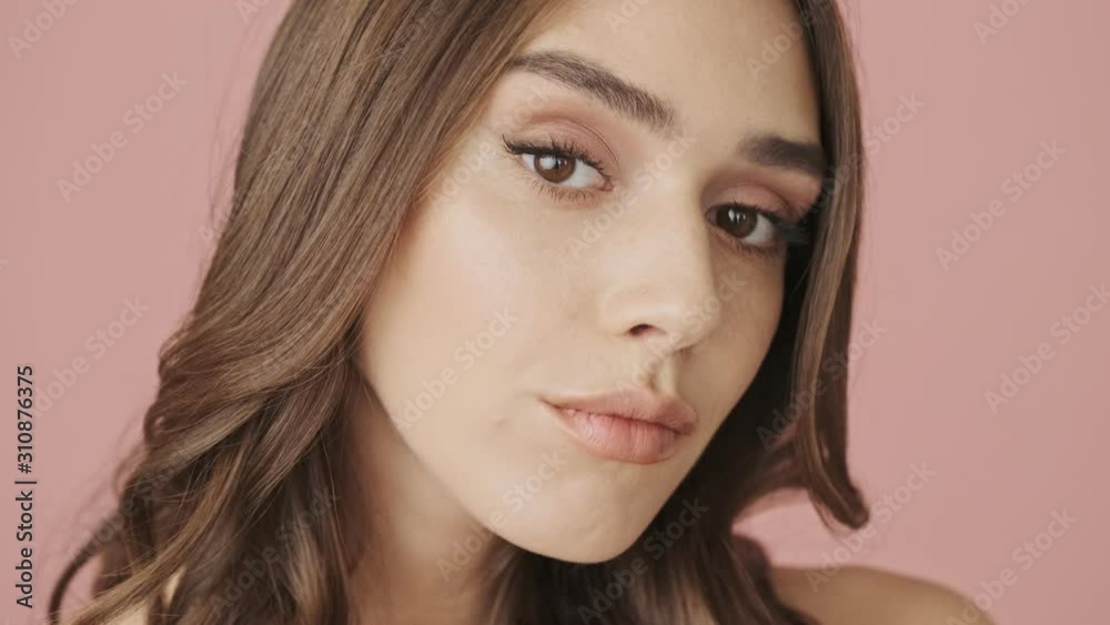 A close-up view of young beautiful woman is raises her brows while looking to the camera isolated over pink background A close-up view of young beautiful woman is raises her brows while looking to the camera isolated over pink background