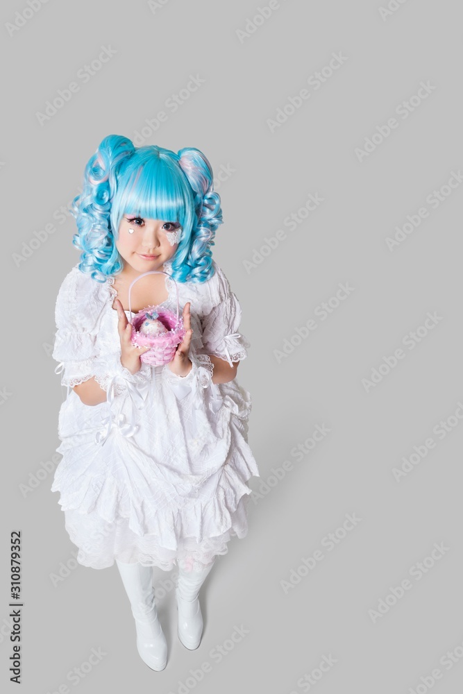 Full length portrait of cute woman in doll costume holding toy basket over gray background