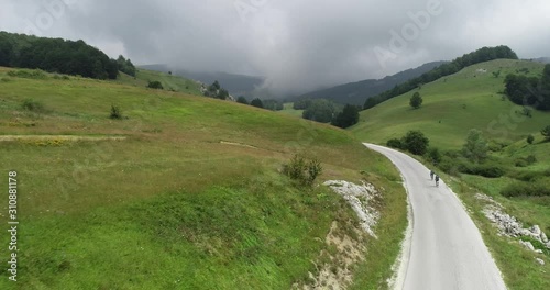 Footage of two cyclists riding their bikes up a mountain roadand preparing themselves for a triathlon contest photo