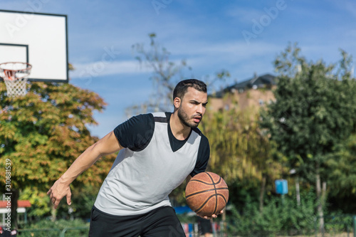 Attractive and strong urban player plays basketball outdoors on a beautiful sunny summer day © Óscar