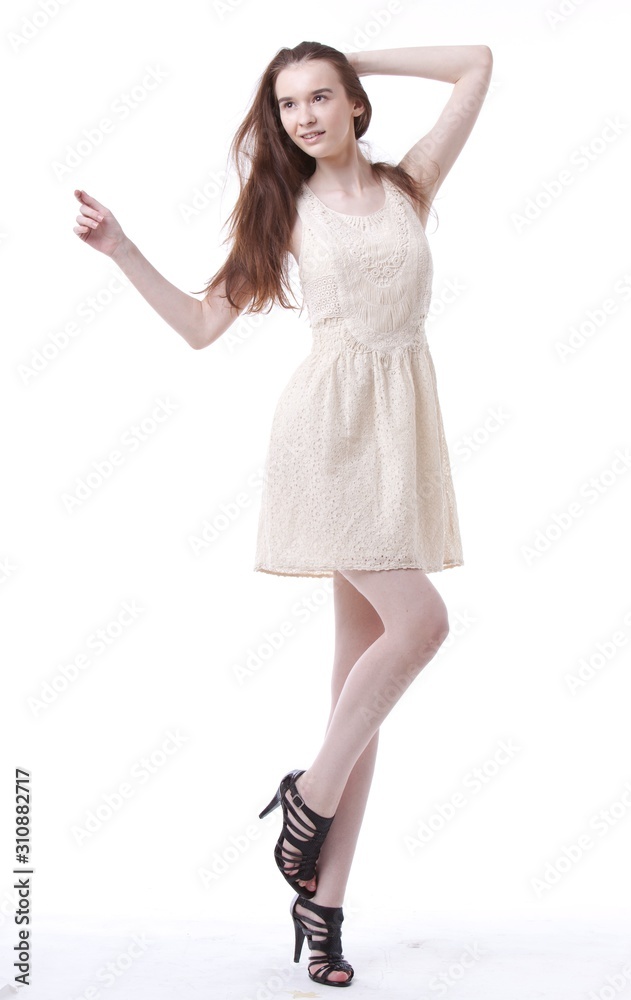 Beautiful young woman in dress with hand in her hair looking away against white background Beautiful young woman in dress with hand in her hair looking away against white background