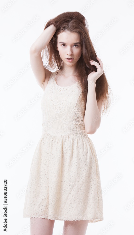 Portrait of beautiful young woman in dress with hand in her hair looking away against white background Portrait of beautiful young woman in dress with hand in her hair looking away against white background