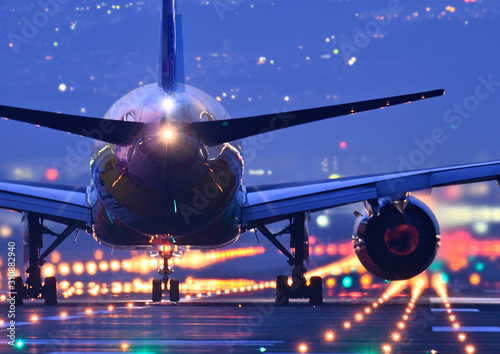 夜の滑走路で離陸する旅客機のクローアップと赤くなったジェットエンジン photo