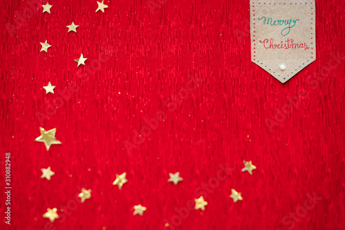 Christmas Theme Background With Copy Space. Christmas background image of red textured surface with copy space and decorated with golden stars made of foil paper for greeting card, poster, advertising