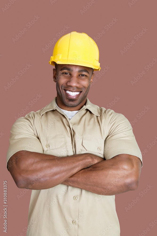 Portrait of cheerful young African construction worker over brown background